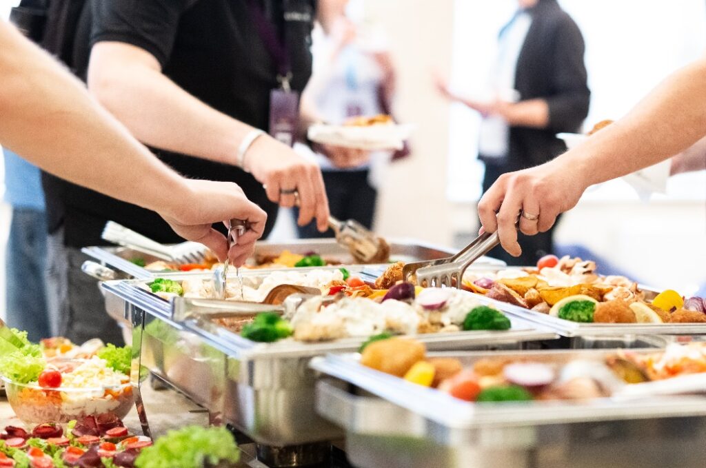 Hände, die das Essen vom Buffet auf der Party abholen.